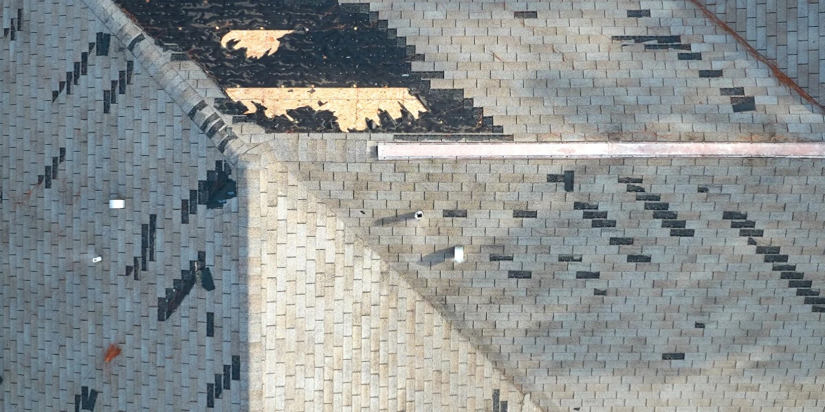 Aerial view of hail-damaged roof shingles showing missing granules and exposed spots after Colorado storm